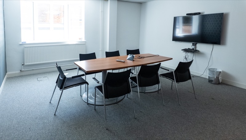 Meeting room with boardroom table, seating for eight and a wall-mounted screen