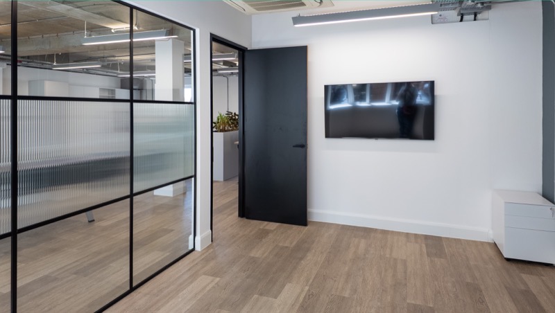 Reeded glass partitioning and wall-mounted screen in the meeting area